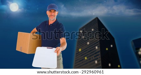 Happy delivery man holding cardboard box and clipboard against city at night