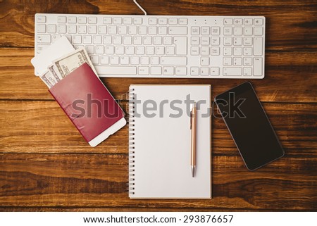 Pen on notepad next to keyboard and smaprtphone on wooden table