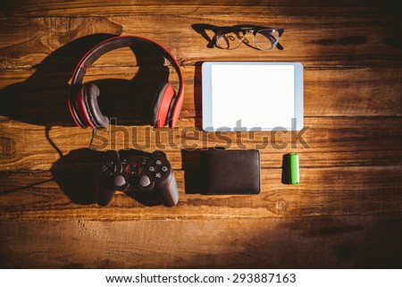 Tablet and USB key next to glasses wallet and joystick on wooden table