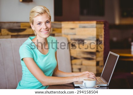 Happy pretty blonde using computer at the cafe