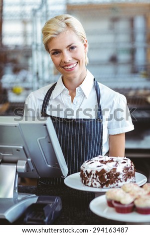 Smiling employee using calculator on counter at the bakery
