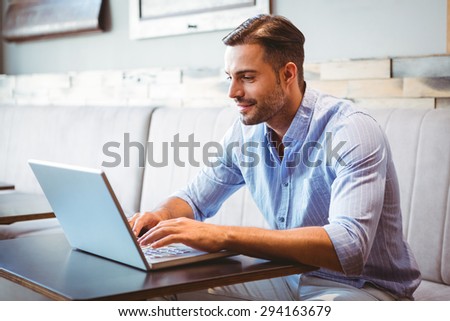 Smiling businessman using his laptop at the cafe