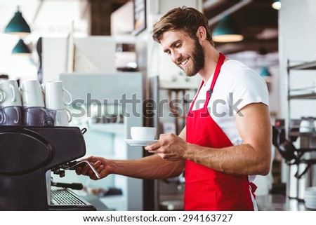 Handsome barista preparing a cup of coffee with the coffee machine