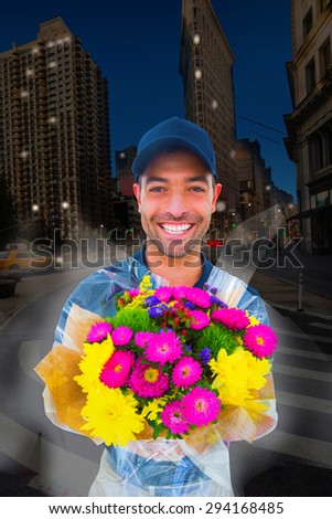 Happy delivery man holding bouquet against city at night