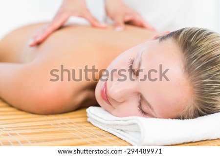 Pretty blonde enjoying a massage smiling at camera at the health spa