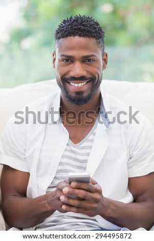 Casual man using his smartphone at home in the living room