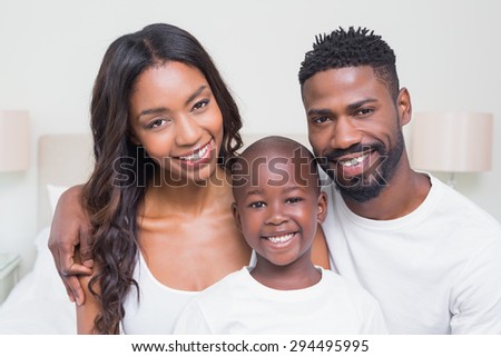 Happy family smiling at camera at home in bedroom