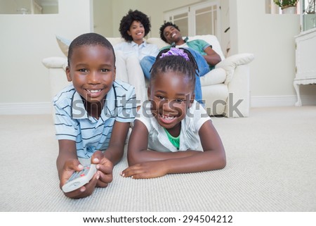 Happy siblings lying on the floor watching tv at home in the living room