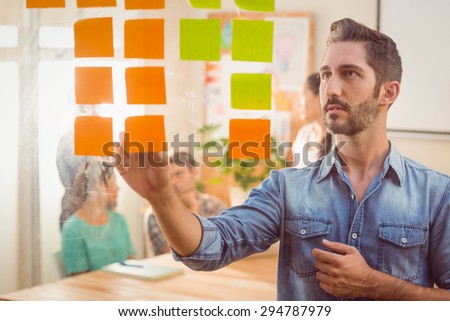 Concentrated businessman looking post its on the wall in the office