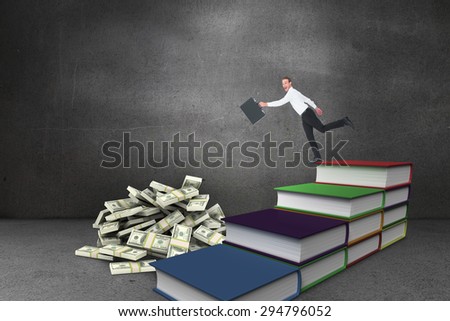 Happy businessman leaping with his briefcase against steps made from books in grey room