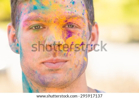 Young man having fun with powder paint on a sunny day