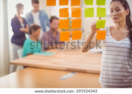 Concentrated businesswoman pointing post its on the wall in the office