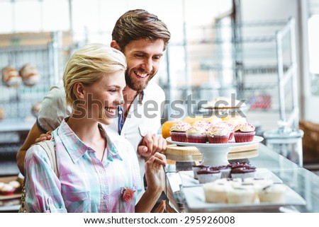 Cute couple on a date looking at cakes at the bakery