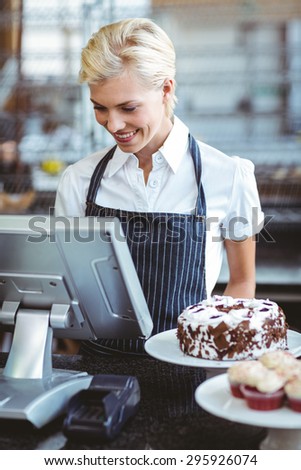 Smiling employee using calculator on counter at the bakery
