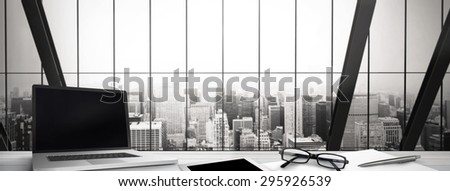 Desk against room with large window looking on city