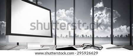Desk against room with large window looking on city skyline