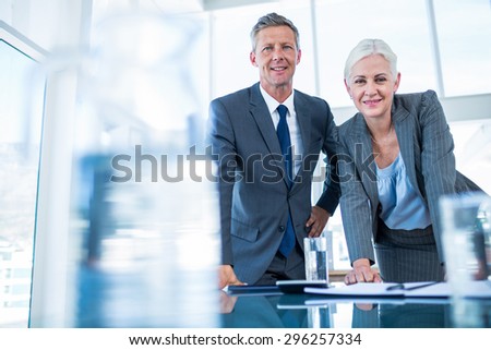 Business people looking at camera behind desk in office