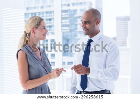 Businessman giving small paper sheet to his colleague in the office