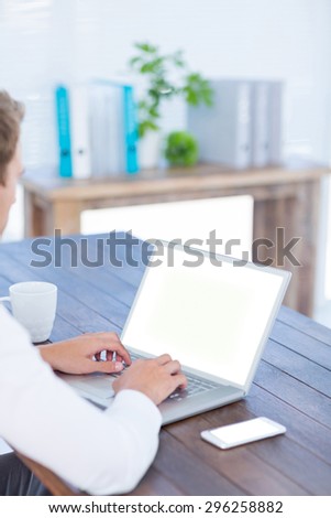 Back view of a businessman typing on laptop in the office