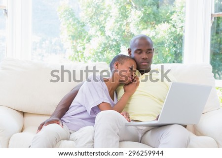 Happy smiling couple using laptop on couch in living room