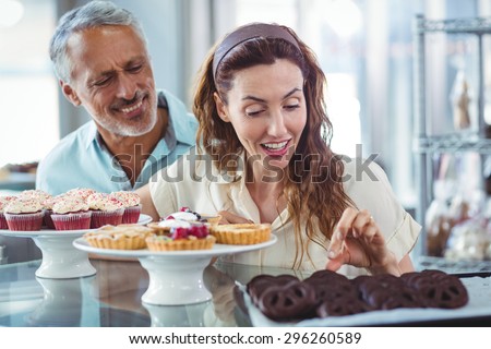 Cute couple choosing chocolate cakes in the bakery store
