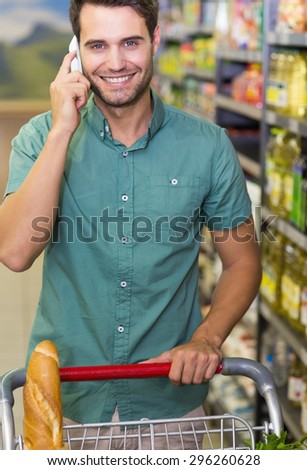 Portrait of smiling man buy food and phoning at supermarket