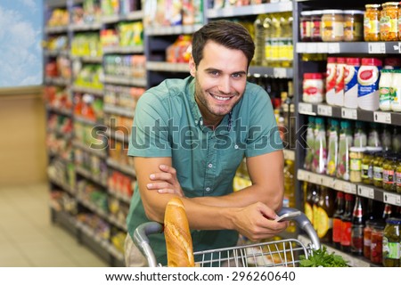 Portrait of smiling man buy food and using his smartphone at supermarket