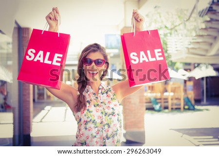 Portrait of euphoric woman holding two sale shopping bags at the shopping mall