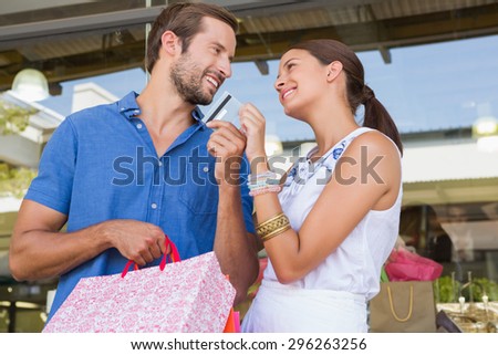 Young happy couple looking each other after shopping holding a credit card