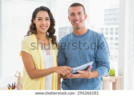 Portrait of smiling colleagues pointing tablet computer in the office
