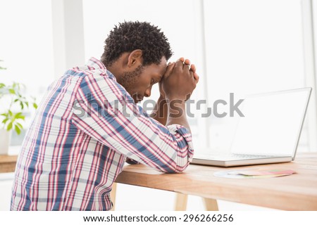 Young businessman being uneasy at his desk in front of the laptop in his office