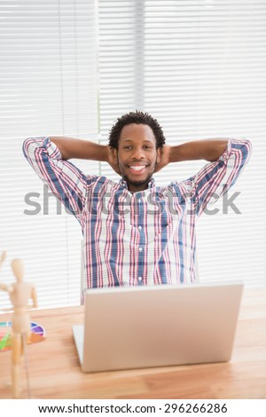Young businessman relaxing at his desk in front of the laptop in the office