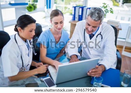 Doctors and nurse looking at laptop in medical office