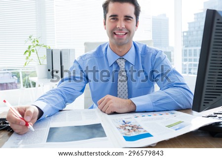 Happy businessman writing at his desk in the office