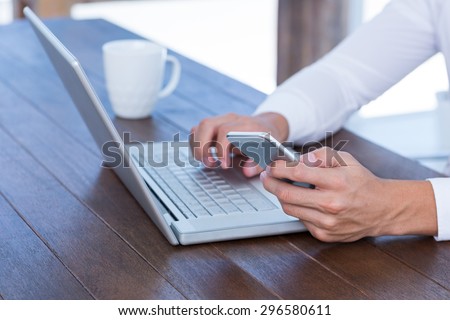 Close up view of a businessman typing on laptop and texting