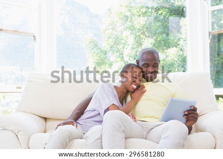 Happy smiling couple using laptop on couch in living room