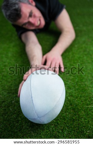 A determined rugby player scoring a try