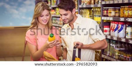 Smiling bright couple buying food products with shopping basket at supermarket
