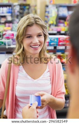 Smiling woman at cash register paying with credit card in supermarket