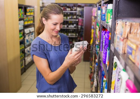 Pretty woman picking box in shelf in supermarket