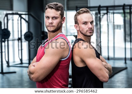 Portrait of two muscular men giving back to back