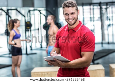 Portrait of a muscular trainer writing on clipboard