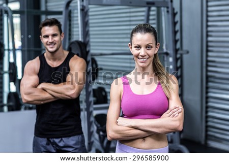 Portrait of an arm crossed muscular couple with woman ahead