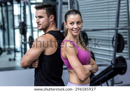 Muscular couple giving back to back with arm crossed