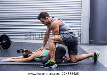 Muscular couple doing a body stretching at the crossfit gym