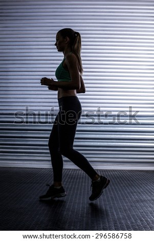 Side view of a muscular woman running in exercise room