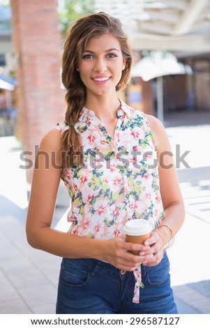 Portrait of smiling woman with coffee to go looking at camera at the shopping mall