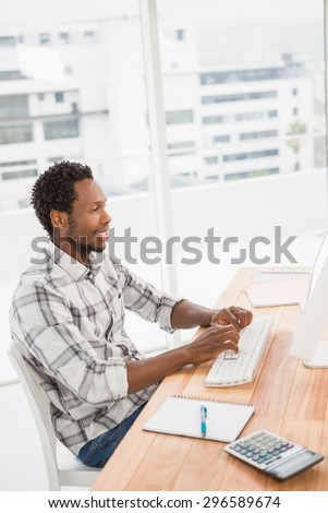 Young businessman sitting at his desk and writing on the computer in the office