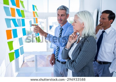 Business people looking at post it on the wall in office