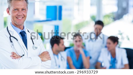 Doctor smiling at camera with colleagues behind in medical office